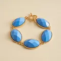 Detailed close-up view of a vintage gold-tone bracelet featuring blue oval resin stones - Blue