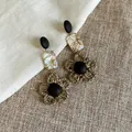 Detail von ethnischen Ohrhängern mit Holzknöpfen, Muschelstücken und gewebten Blumen. - Strohgewebte Blume Stil