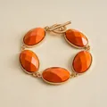 Detail of vintage gold-tone bracelet with faceted orange oval resin stones and toggle clasp. - Orange