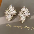 Close-up van elegante marquise-geslepen kristallen oorbellen met gouden strass accenten - Zilveren stift sieraden / Goud-Wit