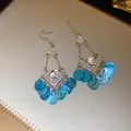 Gedetailleerd overzicht van zilveren ruit oorbellen met blauwe schelp kwastjes en fonkelende stras - Oorhaken (HE35846) / Blauw