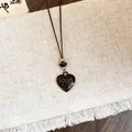 Gros plan du collier avec pendentif cœur léopard, cordon en cuir rustique et perles - Forme de Cœur / Marron