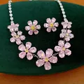 Gedetailleerd overzicht van de roze zirkoon bloemen ketting en oorbellen set op fluweel. - Ketting En Oorbellen Set / Zilver-Roze