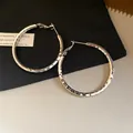 Vue détaillée de créoles en argent avec une texture martelée facettée et des tiges en argent. - Rond Plissé (Tige Argent) / Argent