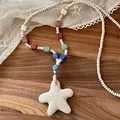 Detailed macro view of colorful volcanic stone beads and a white starfish pendant necklace - White