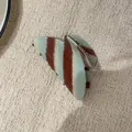 Detailopname van een mintblauwe en bruine gestreepte haarklem van acetaat op stof - S / Blauwe en Koffie Haarklem