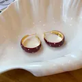 Détail de boucles d'oreilles rétro en émail à pois rouges dans un bol en coquillage. - Or-Rouge