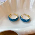 Élégantes créoles en émail bleu à pois présentées sur une coupelle décorative en coquillage - Or-Bleu