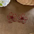Primo piano di orecchini a lobo a forma di fiore rosso con piccoli pois bianchi spray - Rosso