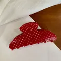 Macro detail of a large red hair claw clip featuring a classic white polka dot pattern design - Red