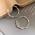 Detailed macro view of silver bamboo-joint hoop earrings with sparkling rhinestones - Silver