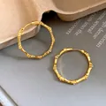 Close-up look at the textured gold bamboo hoop earrings with diamond-like stones - Gold