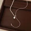 Detailansicht einer asymmetrischen Halskette mit Perlen und gebürstetem Anhänger - Rund / Silber