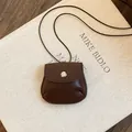 Detail van een vintage bruine lederen mini tasje hanger ketting met drukknop - Ketting Donkerbruin