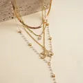 Primo piano di una collana d'oro a più strati con perle, stelle e ciondolo cuore zircone. - Collana a strati / Oro
