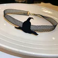 Gros plan du pendentif chapeau de sorcière noir sur un collier ras du cou en résille - Style Chapeau