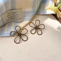 Macro view of brown hollow flower stud earrings with vibrant yellow polka dots on petals - Hollow Flower (Silver Post) / Gray