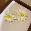 Detail weißer 3D-Blumenohrstecker mit gelben Kristallmitten in einem Holztablett - Silbernadel / Weiß
