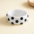 Gedetailleerde weergave van een witte hars armband met stijlvolle zwarte stippen patronen - Wit met zwarte stippen