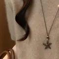 Detailopname van een luipaardprint sterhanger aan een bruine koordketting op een gebreide trui - Ster Stijl / Bruin