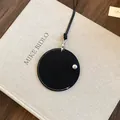 Vue détaillée d'un porte-lunettes rond en cuir noir avec des surpiqûres blanches - Noir