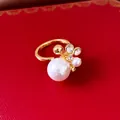 Nahaufnahme eines eleganten Goldrings mit Perlen und Zirkonia im Blumendesign - Blütencluster Offener Ring / Gold