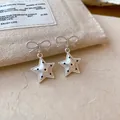 Vue détaillée de boucles d'oreilles nœud et étoile argentées avec motifs à pois noirs - Style Étoile Nœud / Argent