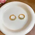 Detailopname van elegante gouden oorringen met delicate groene bloemmotieven op een bord - Bloemen Versierde Oorringen (4#) / Goud-Groen