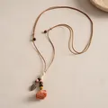 Détail d'un collier ethnique avec rose en céramique et feuille en métal sur cordon. - Marron et Rose