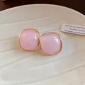 Detail view of pink resin square stud earrings with gold-plated edges on ceramic plate. - Silver Earring Post - Pink