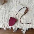 Close-up of minimalist burgundy suede eyeglass holder necklace on textured background - Red
