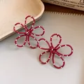 Close-up of red hollow flower earrings with white polka dots and hypoallergenic silver needle - Red