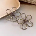 Close-up of brown spray-painted flower earrings with yellow polka dots and hollow design. - Gray