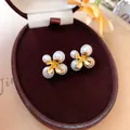 Primo piano di eleganti orecchini a lobo a fiore in oro con perle in un portagioie - Stile Fiore di Perla / Oro