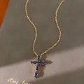 Vista detallada de un collar bañado en oro de 18k con colgante de cruz y circonitas azules - Estilo de Circonita Azul / Dorado
