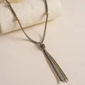 Detailansicht der mehrsträngigen Metall-Quastenkette mit Goldperlen auf einem Steinsockel. - Gold-Silber-Schwarz