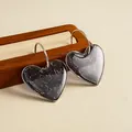 Vue macro de boucles d'oreilles en résine marbrée grise en forme de cœur avec anneaux en C. - Tige de boucle d'oreille en argent - Gris