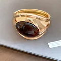 Detailed view of a vintage gold open bracelet featuring a large oval amber resin inlay - Gold Dark Coffee