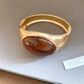 Close-up of vintage golden bangle featuring a large oval amber resin stone - Gold Amber