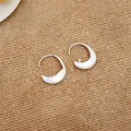 Detailed view of minimalist brushed silver oval hoop earrings on textured burlap background. - Brushed Ear Hook Style / Silver