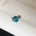 Detailopname van een roestvrijstalen oorknopje met een briljante ronde blauwe edelsteen. - 6mm / Blauw