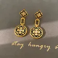 Primer plano de elegantes pendientes colgantes chapados en oro con esmalte y circonitas - Pendientes / Aguja de plata / Dorado Negro