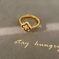 Primer plano de un anillo ajustable chapado en oro con flor de esmalte negro y circonita - Anillo / Dorado Negro