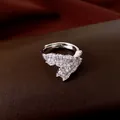 Primo piano di un anello aperto in argento con zirconi geometrici su pelle marrone. - Argento
