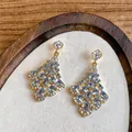 Detail of elegant gold drop earrings with light blue teardrop crystals and rhinestones - Gold-White