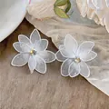 Detailopname van elegante witte mesh bloemoorbellen met sprankelende zirkonia accenten. - Wit