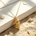 Close-up of golden stainless steel conch shell pendant on a sunny beach background - 18K Gold Plated