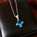 Close-up of a square-cut sky blue zircon pendant necklace against a black leather background - Necklace - Silver - Blue