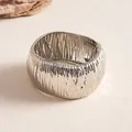 Detailed view of metallic silver cuff bracelet with unique crinkle texture and spring closure. - Silver
