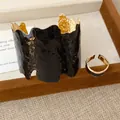 Detail von unregelmäßigem schwarzen Emaille- und Gold-Armreif mit passendem Ring - Ring Armband Set / Schwarz
